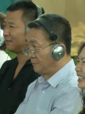 The cover image features a group of people wearing headphones. Two men are in the foreground, one wearing glasses and a light blue collared shirt, and the other wearing a black shirt and headphones. A woman is visible to their right, smiling. The composition is well-lit and focused on the individuals' faces.