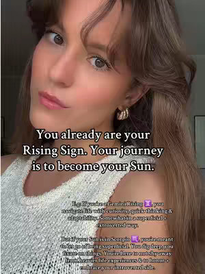 A selfie-style shot featuring a woman with long, wavy light brown hair, wearing a white tank top and gold hoop earrings. She's looking toward the camera with a slightly pursed expression and a soft make-up look. Text overlays are added, including the primary message 'You already are your Rising Sign. Your journey is to become your Sun.' Below this, additional text explains the concepts of Rising and Sun signs, with some examples.