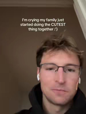 A selfie-style shot featuring a fair-skinned man with short, light brown hair. He's wearing glasses and white earbuds. The background is a plain, neutral brown or tan, allowing the focus to remain on the individual. Text overlays at the top.