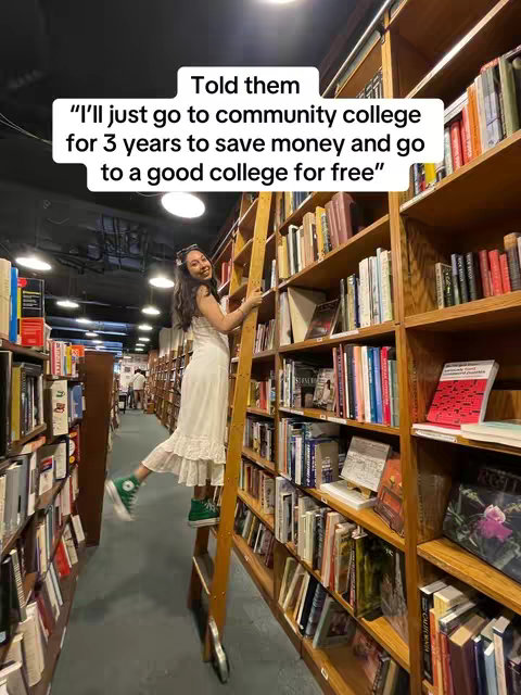 A young woman in a white dress standing on a ladder in a library, smiling towards the camera with bookshelves in the background. Overlaid text.