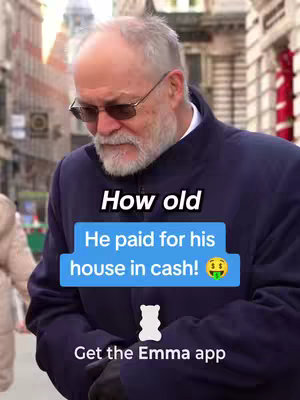 An older gentleman with a white beard and sunglasses is standing in front of a blurred city backdrop. He's wearing a navy blue coat and looking slightly downward. Text overlays include the question 'How old' and a box saying 'He paid for his house in cash!' along with the Emma app logo.