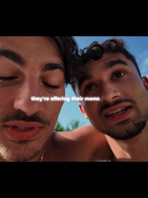Two young men are shown in a close-up selfie. The man on the left has his eyes closed. The man on the right has his mouth open as if speaking. The words 'they're offering their moms' are shown in text overlay at the center of the image.