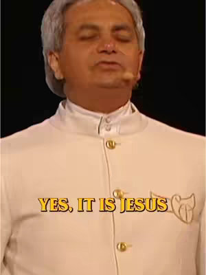 The image features a man in a light-colored suit with a white collar, looking slightly upward with closed eyes. Text overlaid in yellow fonts on a black background reads 'YES, IT IS JESUS'. The composition is a medium shot centered on the individual, with a focus on the upper body and face, and a dark background.