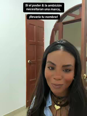 A selfie-style video with a woman looking towards the camera. The background includes a light-colored wall, a wooden door, and a partial view of a second door.