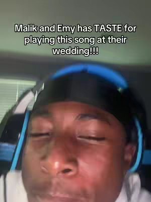 A close-up shot of a Black man wearing a black durag and gaming headphones. His eyes are closed and he is smiling slightly. Text overlay informs that Malik and Emy have good taste for playing this song at their wedding.