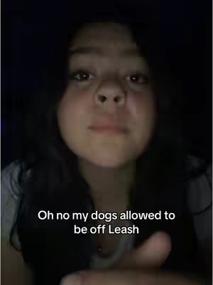 A close-up shot of a young woman against a dark background. The woman has dark hair and a slightly open mouth. Text overlayed says, "Oh no my dogs allowed to be off Leash".