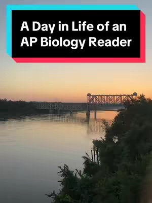 A scenic landscape at dusk. A wide river flows under a large metal bridge. The sky is a gradient of orange and blue. The overall composition is balanced, with the bridge and river contributing to a sense of depth and perspective.