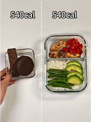 The cover image is a split-screen displaying two side-by-side clear glass containers. The left side features a square container holding a chocolate wafer candy bar and a chocolate-covered cookie. The right side shows a divided container with a portion of grilled chicken with red peppers, white rice, green beans, and avocado slices. Above both containers is the text '540cal'. The background is plain white.