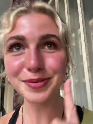 The cover image features a close-up shot of a young woman with blonde hair. She is pointing her index finger towards her own face, with a warm and expressive smile. The background is slightly blurred, suggesting an indoor setting.
