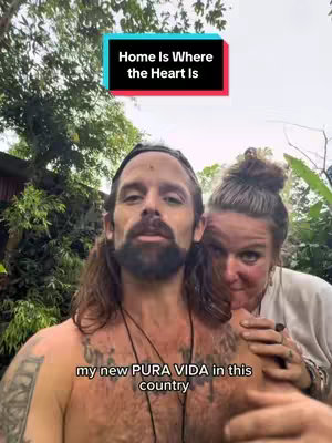 A selfie-style shot featuring a man with long hair and a beard in the foreground, his torso exposed, with a woman partially visible behind and to his right. They appear to be outdoors, with trees and foliage in the background, and text overlays indicating the video's theme.