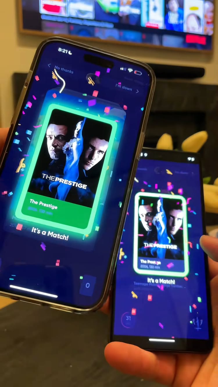 Two smartphones are held in front of a blurred background featuring a television screen. Both phones display the app interface, with a movie poster labeled "The Prestige" on a screen and a celebration effect made of confetti.