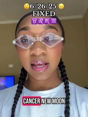 A selfie-style image featuring a dark-skinned person looking directly at the camera, wearing diamond-shaped clear glasses and a white shirt. Pigtail braids frame the face. Overlaid text includes the date "6/26/25," the word "FIXED," zodiac symbols, and the phrase "CANCER NEW MOON."