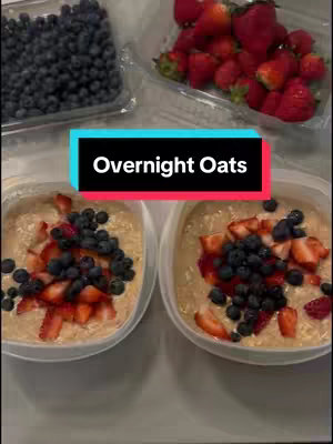 The image shows two bowls of overnight oats, each topped with fresh blueberries and sliced strawberries. In the background, containers of blueberries and strawberries are visible. A text overlay reads 'Overnight Oats.'