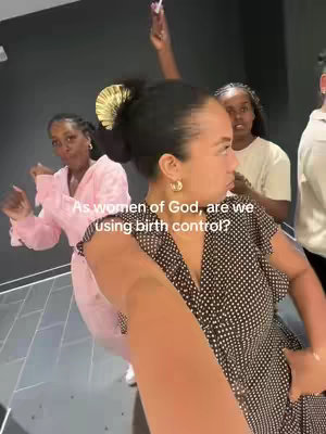 A selfie-style video shows a woman in a polka-dot dress extending her arm, seemingly filming. Three women are in the background, one in pink pajamas and other with her arm raised in a playful way. Text overlay gives the viewer the question, 'As women of God, are we using birth control?'