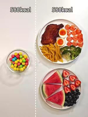 The cover image is split vertically down the middle. On the left is a small glass bowl filled with colorful, round candies. On the right side, there are two plates of food. The top plate has a piece of chicken, french fries, two halves of eggs, broccoli, and shrimp. The bottom plate has watermelon slices, strawberries, and blueberries. Each side is labeled with '580kcal' in white text, and the background is white.