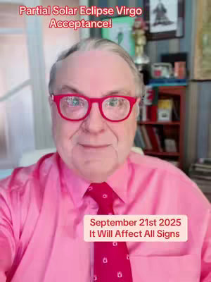 A man in a pink button-down shirt, a red tie, and red-rimmed glasses is centered in the frame. Text overlays are on the top and bottom of the frame. The background suggests a home office setting, with bookshelves visible.