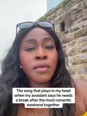 A selfie-style video cover image featuring a Black woman with dark hair and sunglasses perched atop her head. The background has a brick wall. A text overlay at the bottom displays a message.