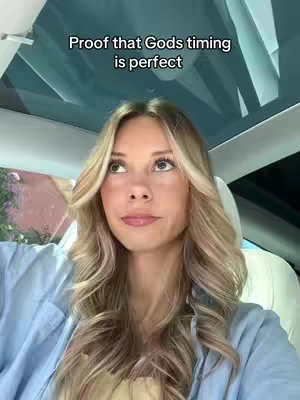 A woman with long blonde hair is sitting in a car, looking up with a thoughtful expression. The car's interior is visible, with a clear roof and headrest. A text overlay is visible at the top of the image.