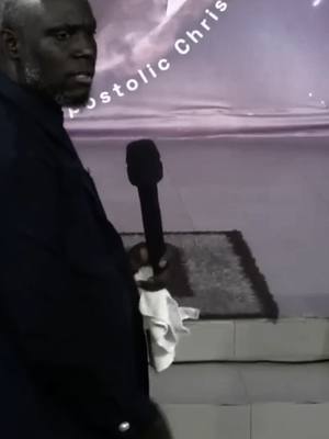 The cover image features a man on a stage holding a microphone. The man is dark-skinned with short hair and a beard. He is wearing a dark suit, and a white handkerchief is tucked into his jacket pocket. A muted backdrop of a cloudy, purple sky is visible behind him, with text written above. The man's gaze appears to be slightly off to the side.