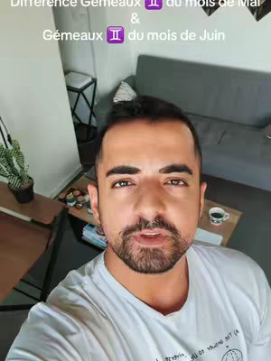 The cover image is a selfie-style shot of a man from the chest up indoors. The background is a room with a grey sofa, a side table with items on it, and a plant. The man is wearing a white t-shirt, and is looking directly at the camera, apparently speaking. Text overlay is present at the image top.