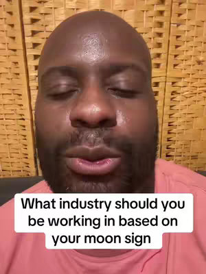 The cover image features a close-up of a Black man with a bald head and a short beard. He is wearing a pink t-shirt. The background is a woven pattern. The text overlay displays the question, What industry should you be working in based on your moon sign?. The man's eyes appear closed.