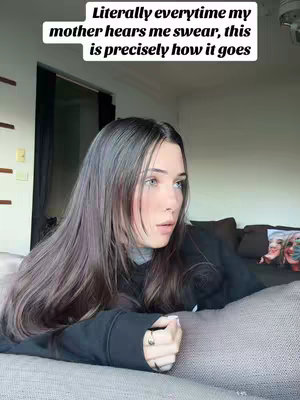 A young woman with long, dark hair is lying on a couch with a look of surprise on her face. Text overlayed on the image says, "Literally everytime my mother hears me swear, this is precisely how it goes."