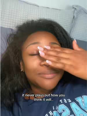 A young woman with dark, wavy hair is lying in bed, covering her eyes with her right hand. The background includes a white pillow on a bed, possibly a bedroom setting. A text overlay with the phrase "it never plays out how you think it will.." appears at the bottom of the image.