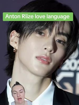 The image shows a close-up of a young Asian male with a green text overlay in the top left. In the bottom corner, a woman with bright makeup is visible in the frame. The background appears to be a dark color.