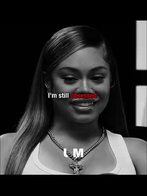 A black and white close-up of Latto, with the text overlayed over her lips. She is wearing a white tank top and a necklace. The background is a dark, studio setting.