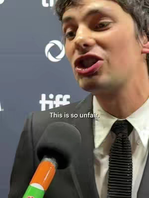 A man in a suit is speaking into a microphone. The text overlay 'This is so unfair' appears near the bottom of the image.