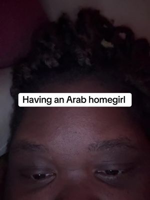 The image is a close up shot of a person's face. The person appears to be lying down. The background is blurred, suggesting a dark or dimly lit setting. The text overlay is in a white box and reads 'Having an Arab homegirl'.