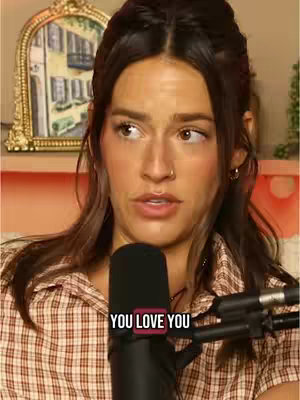 A medium shot features a woman looking slightly off-camera, with a microphone in front of her. The background includes a framed picture and soft lighting, while text overlays read 'YOU LOVE YOU'. She is wearing a plaid shirt with her hair half up.