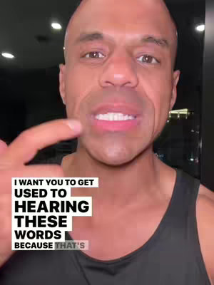 A medium shot shows a smiling man with a bald head, dark skin, and a black tank top. He is pointing with his left index finger, and there is overlaid text in a white box.