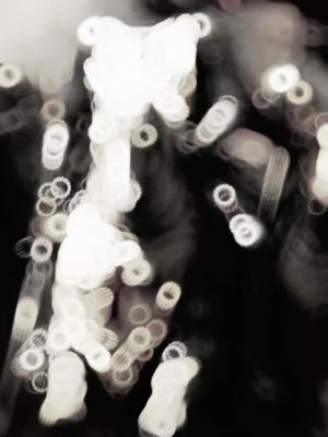 Abstract image with a dark background and blurred white circular and linear shapes, resembling lights or a digital effect. The shapes are arranged in a somewhat symmetrical pattern.