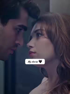 A close-up shot of a man and woman with their faces close, almost touching. The woman is the focus, with her face in profile, looking slightly upwards. The man is partially visible from the side, his face angled towards hers. The overall scene is dimly lit with a dark background, creating an intimate and possibly romantic mood. Added text overlay at the bottom.