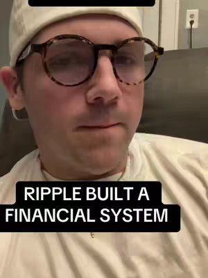 A person wearing clear-framed glasses and a white beanie stares directly at the camera. Overlay text on the image reads 'RIPPLE BUILT A FINANCIAL SYSTEM'. The background appears to be a room with a wall and an electrical outlet visible.