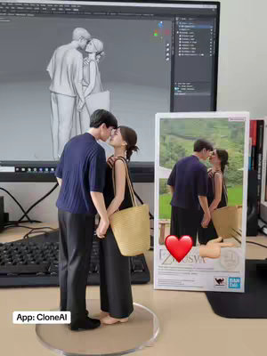 The cover image showcases a couple sculpted as a 3D model, kissing intimately. The pair, rendered in a 3D art style, is depicted holding hands, conveying a sense of romantic closeness. The setting includes a desktop computer beside the couple along with a replica box of the image. An app name is labeled.
