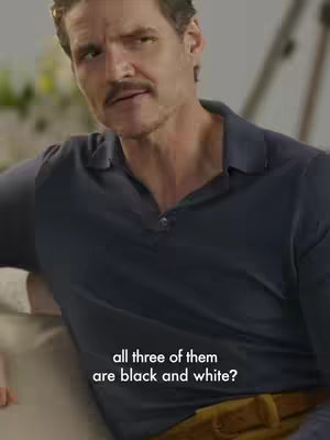A man with short brown hair and a mustache sits and looks at the camera. He wears a navy blue polo shirt and has a light-skinned complexion. The text 'all three of them are black and white?' appears below him.