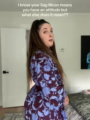 A woman stands in a room, seen from the side, wearing a dress with a dark maroon background and blue floral pattern. Text overlay sits on the top portion.