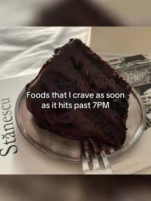 A close-up shot of a slice of chocolate cake on a silver plate. A fork rests on the plate. The background is a white sheet with text printed on some of it. The text overlay reads: Foods that I crave as soon as it hits past 7PM.