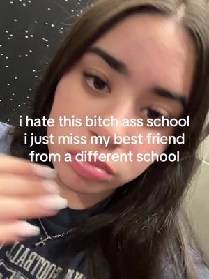 A young woman with long, dark hair is looking at the camera with a slightly pursed expression in a selfie. White text overlay is present. The background is of a spotted pattern.