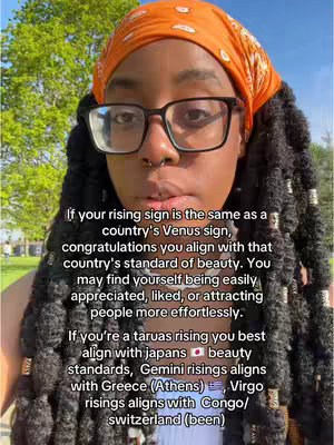 A woman with locs, glasses, and an orange headscarf stands outdoors with text overlaid on the image. The text provides an astrology reading.