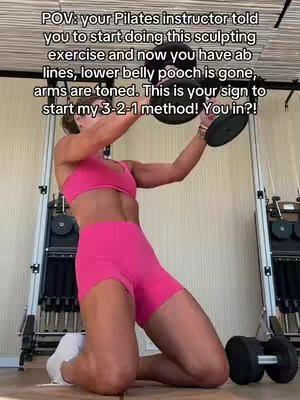 The cover image shows a woman kneeling on a workout mat, performing a Pilates exercise. She is wearing a bright pink sports bra and shorts. She's holding onto a weight and is angled upwards. The background has other workout equipment visible and a window with a light or view of the outside.