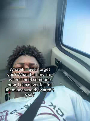 A selfie-style image with a man in the foreground. The man is wearing a white shirt with an emblem and a seatbelt. The background reveals the interior of a vehicle, likely a train, with a window showing a bright blue sky. Text overlays are present, superimposed on the image.