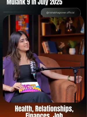 A woman with long, dark hair is seated, facing slightly to her left, and speaking into a microphone. She wears a black top under a purple blazer. The backdrop includes bookshelves, soft warm lighting, and a mic aimed at her. A magazine with colorful text is held in her lap, and in the top right corner there is text that says '@rishabhagrover.official'. The bottom part is showing a hook that says 'Health, Relationships, Finances, Job'.