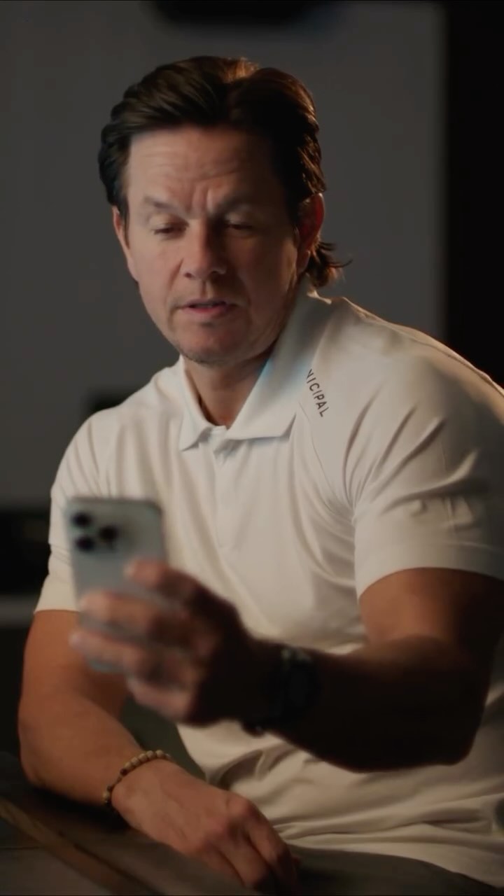 The cover image shows Mark Wahlberg looking at his phone. He is wearing a white polo shirt with a logo on the sleeve and a watch. The background is a simple, neutral gray.