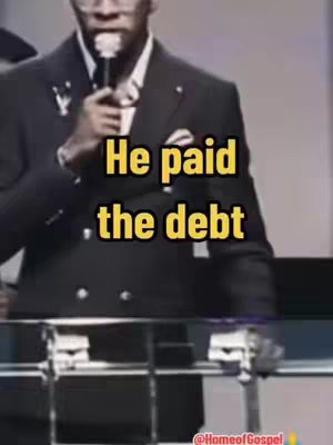 A man in a dark suit is standing behind a podium, holding a microphone. Overlaid on the image is bold yellow text.