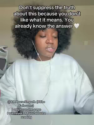 A woman with curly hair is centered in a selfie-style shot. The background is blurry, suggesting a room with a light-colored wall. Overlay text reads: 'Don't suppress the truth about this because you don't like what it means. You already know the answer.' Additional smaller text at the bottom displays a username and some details.