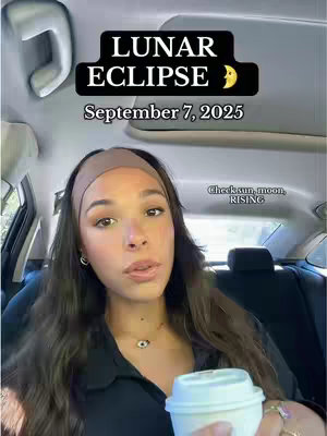 A woman in a black top and headband is seated in a car, holding a white coffee cup. Overlayed on the image is a black box containing text in white, reading 'LUNAR ECLIPSE' above the date 'September 7, 2025'. The image is well-lit, featuring a clear view of the woman's face and the car interior.