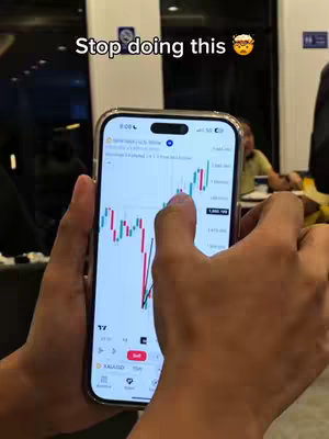 A person holding a smartphone with a financial chart displayed, overlaid with white text at the top and a person in the background.